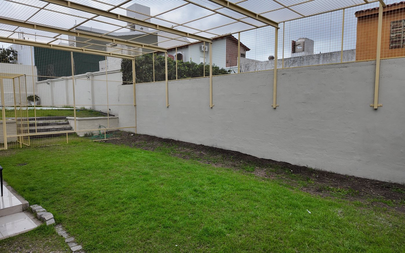 El catio: un patio con pasto, cerrado con malla por arriba y por los costados